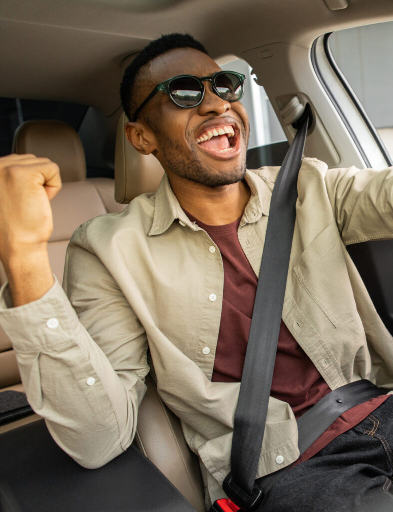 A joyful African American in glasses dances in a car