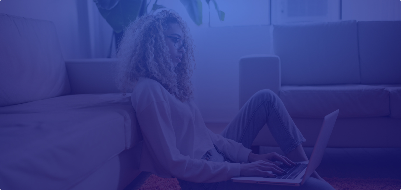 Girl with curly hair sitting on the floor on her laptop