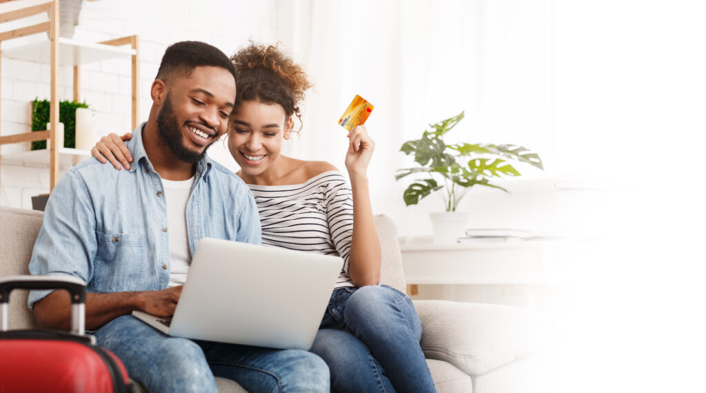 African American couple holding a credit card and looking at a laptop