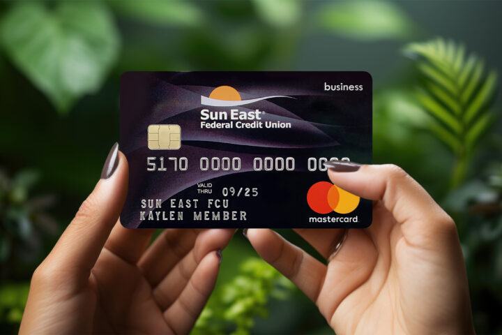 Close up of female hands holding a credit card with green leaves