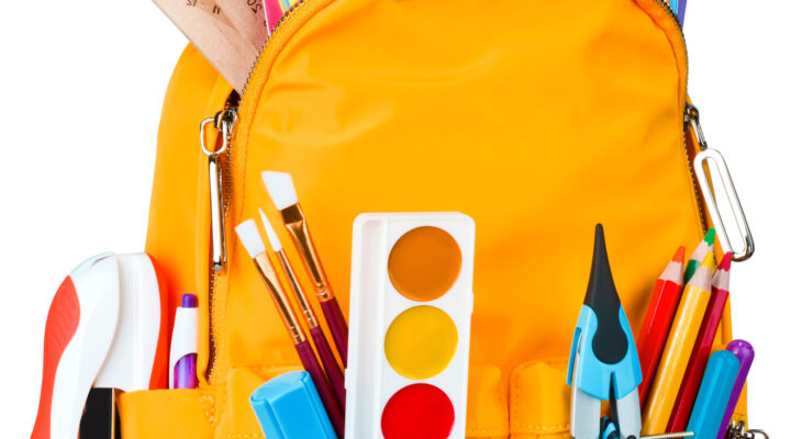 Yellow school backpack with school supplies isolated on white background