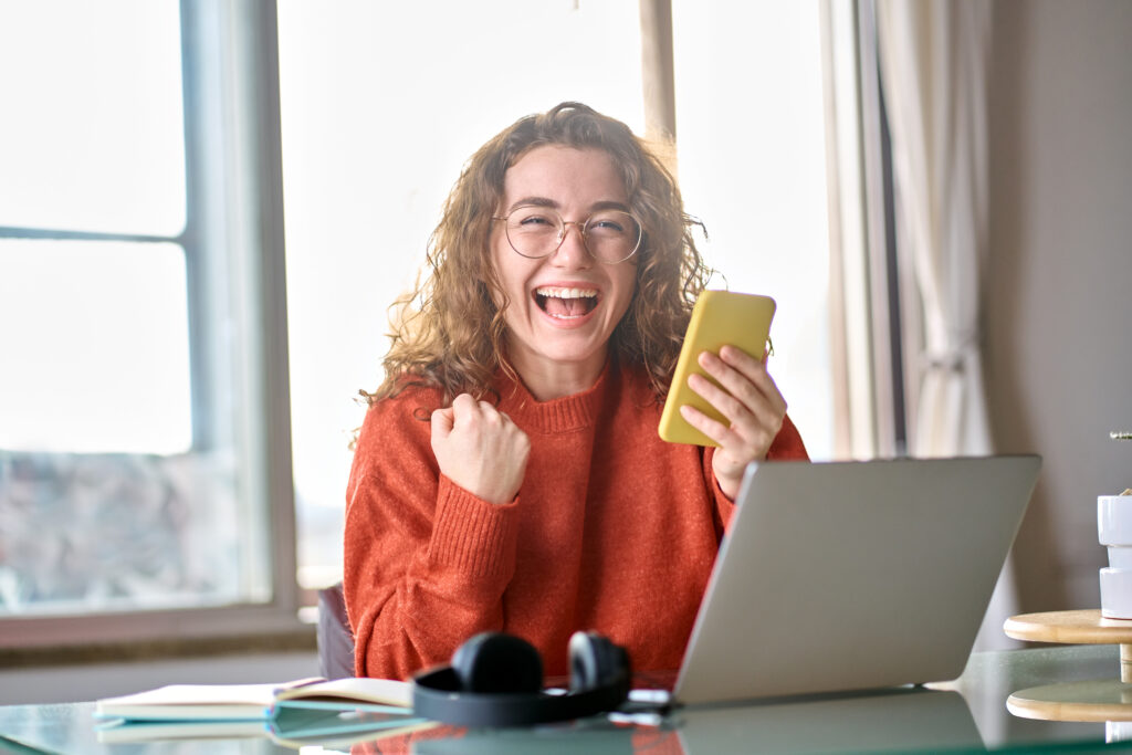 Excited girl holding yellow cell phone