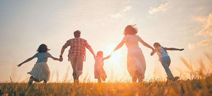 family running into the sunset in a field