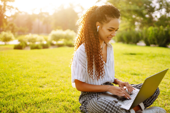 woman using laptop computer sitting on grass