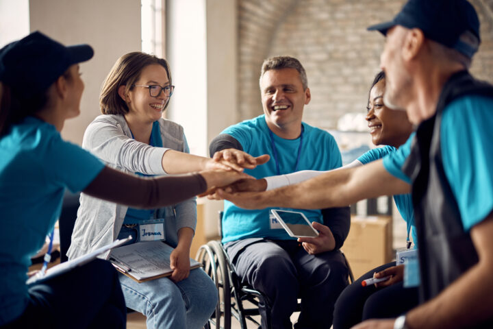 group of people sitting around in a circle - hands to the center - man in wheelchair