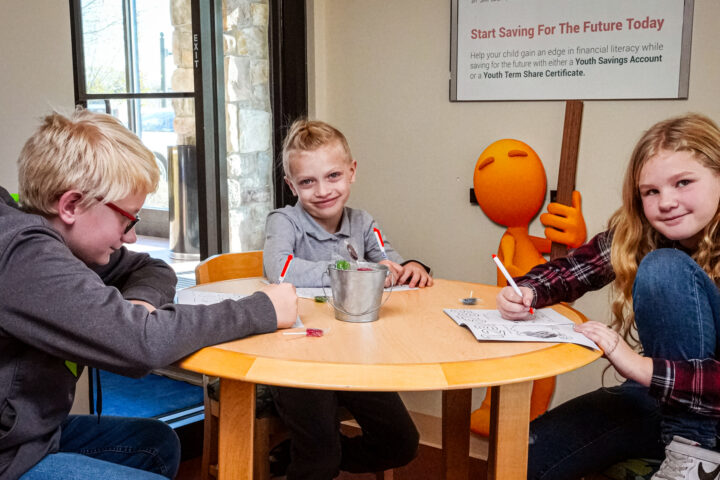 Three children coloring at a table.