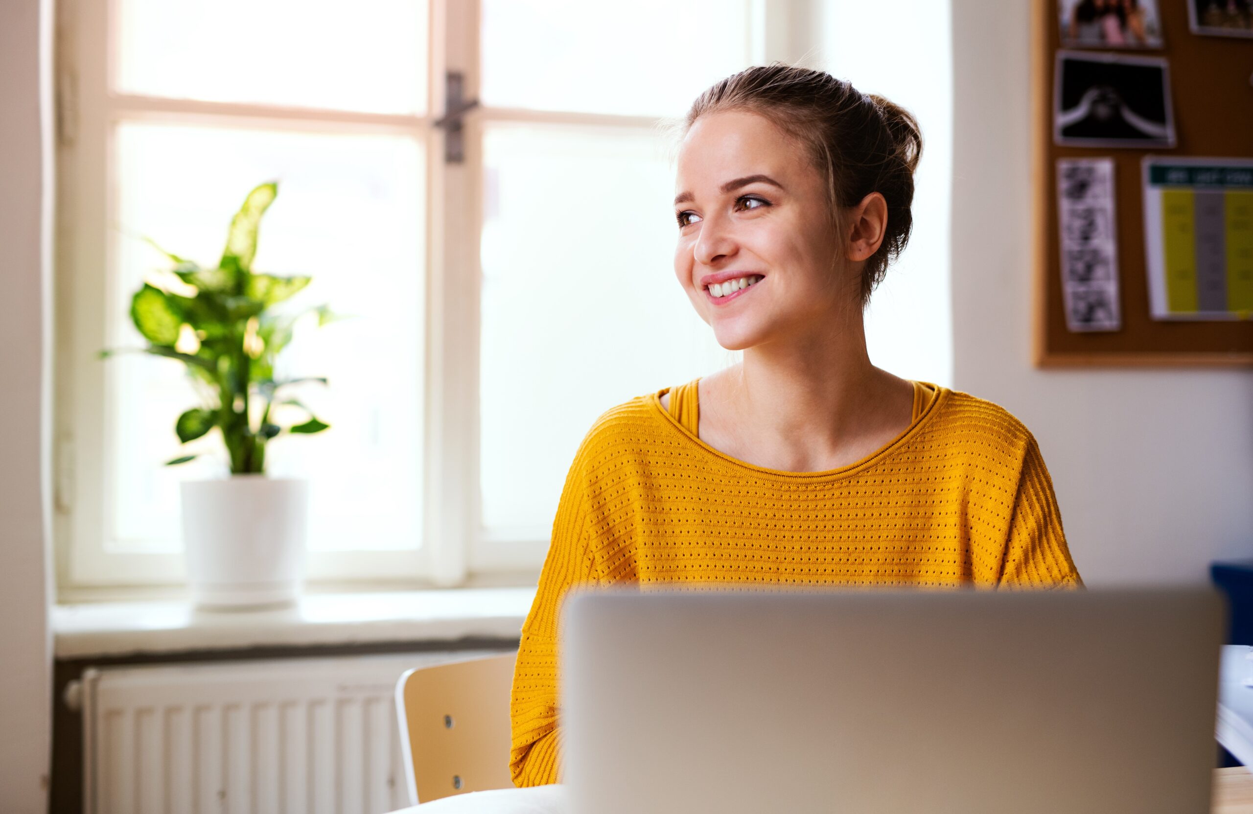 A young female student sitting at the table, using laptop when studying.