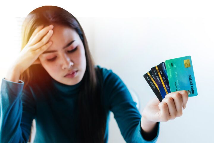 stressed young pretty woman headache holding many credit card in hand and worried about bill in home office, plan money cost saving, shopping online, investment, business finance and expenses concept