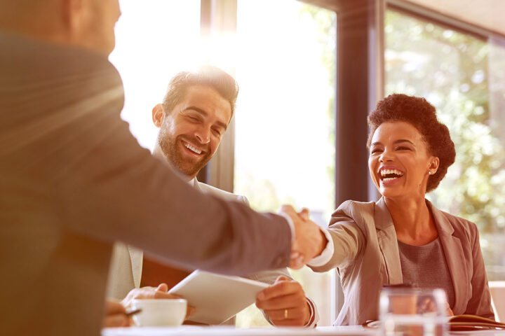 Couple shaking hands with man in suit